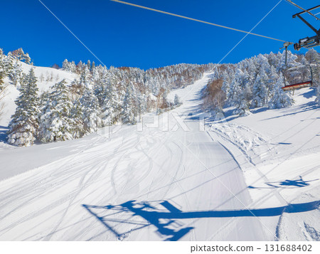 A view of the packed snow slopes from a ski lift (Yokoteyama, Shiga Kogen, Nagano Prefecture) 131688402