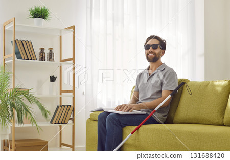 Happy sightless man is sitting on couch at home and reading texts in Braille book Happy sightless man is sitting on couch at home and reading texts in Braille book 131688420