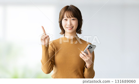 A smiling woman giving directions with a smartphone A smiling woman giving directions with a smartphone 131689060