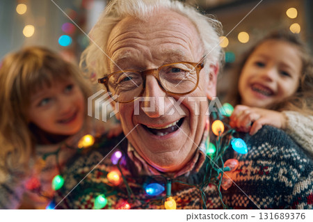 Happy grandfather with kids smiling while wrapped in colorful Christmas string lights 131689376