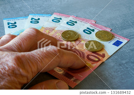 Hand holding Euro banknotes and coins on table, concept of money, finance, savings and expenses 131689432