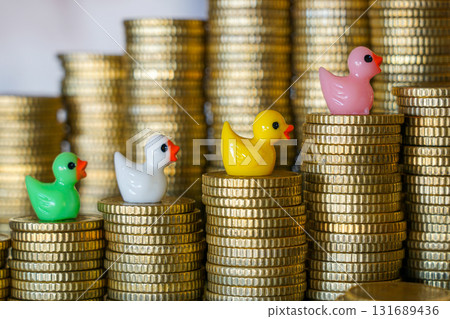 Colorful toy ducks on stacks of gold coins, concept of investment growth, finance and savings Colorful toy ducks on stacks of gold coins, concept of investment growth, finance and savings 131689436