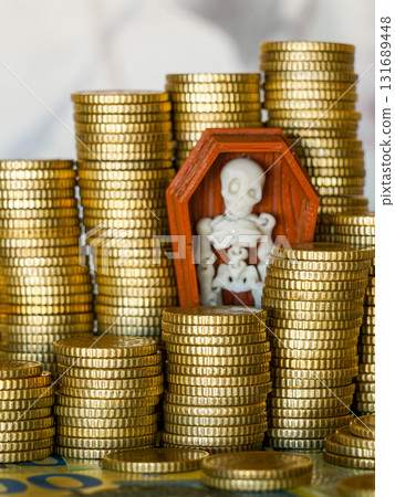 Skeleton in coffin among stacks of gold coins symbolizing greed, death, corruption, and wealth 131689448