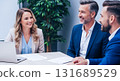 Three business people smiling and collaborating around a table in a modern office setting indoors 131689529