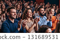 Audience clapping and smiling in a theater during a performance with people enjoying the show together 131689531