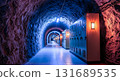 Illuminated tunnel with electrical panels lining the walls in a cave like structure underground 131689535