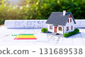 A model house sitting on blueprints with an energy efficiency rating chart and green background trees 131689538