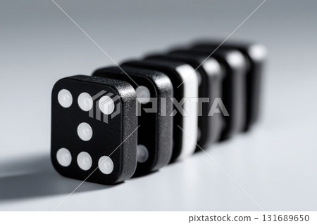 Classic black and white dominoes lined up in a creative arrangement on a white surface 131689650