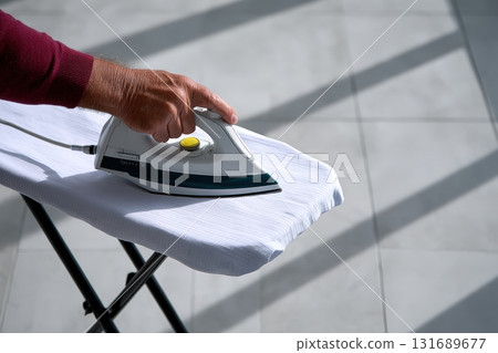 Ironing clothes in a bright room with sunlight streaming through the windows 131689677
