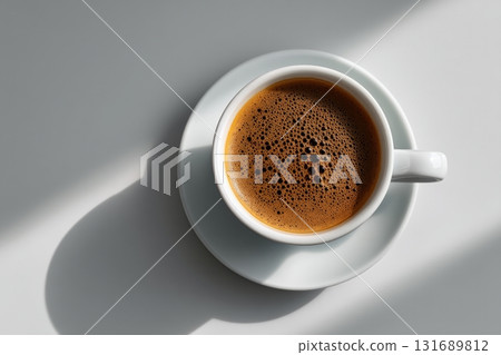 Detailed view of a freshly brewed coffee cup on a white saucer in bright sunlight 131689812