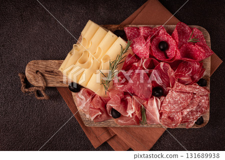Assorted meat, appetizer, prosciutto, salami and ham, with maasdam cheese and olives, on a wooden board, breakfast, top view, close-up, no people 131689938