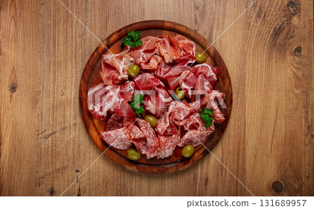 Assortment , sliced meat appetizer, prosciutto, salami and ham, with olives, on a wooden board, breakfast, top view, close-up, no people, Assortment , sliced meat appetizer, prosciutto, salami and ham, with olives, on a wooden board, breakfast, top view, close-up, no people, 131689957