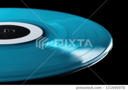 Vibrant blue vinyl record spinning on turntable with light reflections in dark environment 131690078