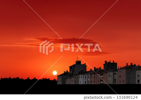 Sunset over buildings creates a warm glow in the evening sky 131690124