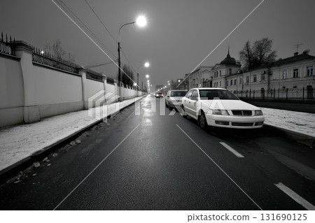 Cars parked along a quiet street on a rainy night in a city with snow 131690125