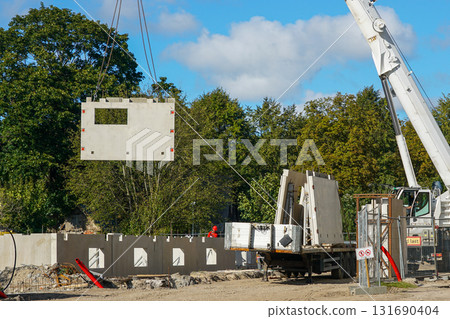 Crane lifting precast concrete wall panel at multi-story residential building construction site Crane lifting precast concrete wall panel at multi-story residential building construction site 131690404