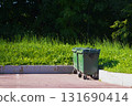Green garbage bins on the street, placed on a paved area near the curb.  131690414