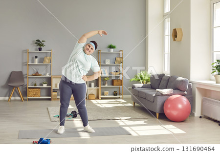 Overweight chubby woman doing side bends at home Overweight chubby woman doing side bends at home 131690464