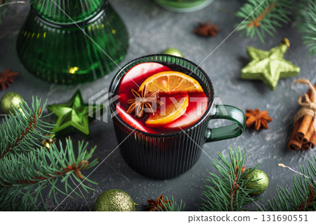Holiday Mulled Wine with Orange and Apple in Green Mug Surrounded by Christmas Decor Holiday Mulled Wine with Orange and Apple in Green Mug Surrounded by Christmas Decor 131690551