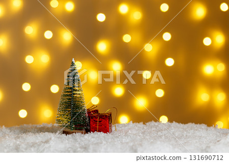 Christmas tree in snow with gifts on glowing lights bokeh background 131690712