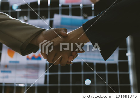 Business people shaking hands in office. Two business partners shaking hands after signing a contract in office. 131691379