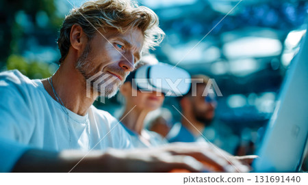 Smiling older man with gray hair and beard working on a laptop in a modern coworking space 131691440