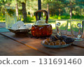 Fresh flowers and greenery decorate the table, creating a cozy and inviting atmosphere for a summer tea gathering. 131691460