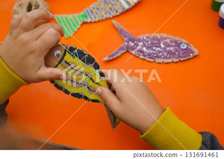 Craft a fish model from cardboard, thread, and paint, with detailed steps, on an orange background. 131691461