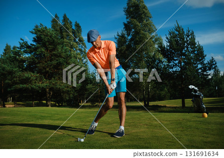 Golfer swings at a sunny course in summer, showcasing perfect form and technique while preparing for the next shot 131691634