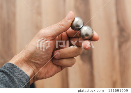 A man's hand holds two CNC metal spheres in warm daylight. A symbol of Earth's poles and the power to control their balance. Precision meets metaphor. A man's hand holds two CNC metal spheres in warm daylight. A symbol of Earth's poles and the power to control their balance. Precision meets metaphor. 131691909