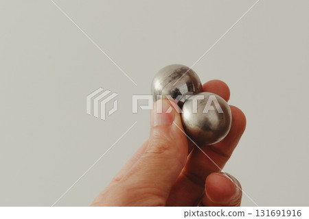 A man's hand holds two CNC metal spheres in warm daylight. A symbol of Earth's poles and the power to control their balance. Precision meets metaphor. A man's hand holds two CNC metal spheres in warm daylight. A symbol of Earth's poles and the power to control their balance. Precision meets metaphor. 131691916
