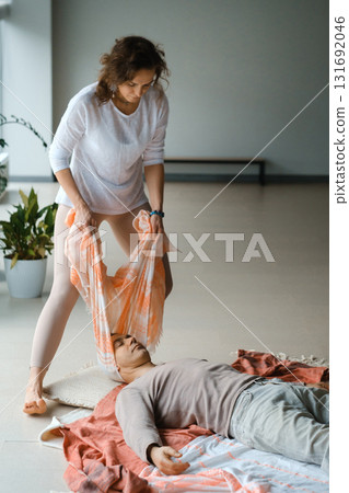 Woman practicing healing techniques on man lying down in a bright indoor space during a wellness session focused on relaxation and mindfulness 131692046