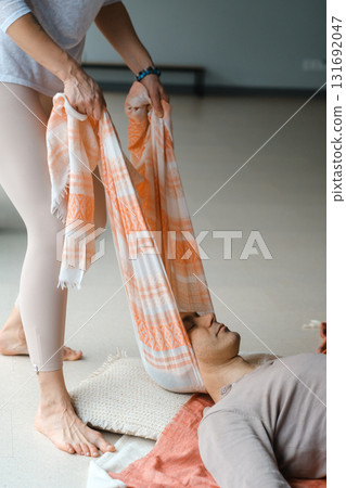 Woman practicing healing techniques on man lying down in a bright indoor space during a wellness session focused on relaxation and mindfulness 131692047