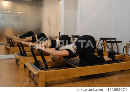 Woman practicing pilates on reformer machine in modern fitness studio during morning class focusing on flexibility and strength 131692074