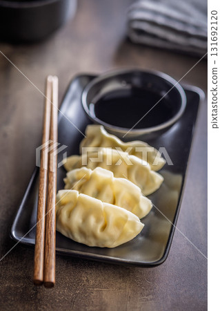 Traditional japanese gyoza dumplings and soy sauce on kitchen table. 131692120