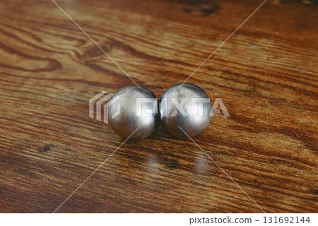 Two CNC spheres on a wooden desk in natural light. A symbol of polarity, brain hemispheres, control, geomagnetic shift, and psychedelic transformation. 131692144
