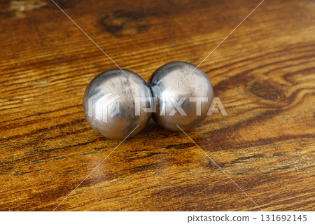 Two CNC spheres on a wooden desk in natural light. A symbol of polarity, brain hemispheres, control, geomagnetic shift, and psychedelic transformation. Two CNC spheres on a wooden desk in natural light. A symbol of polarity, brain hemispheres, control, geomagnetic shift, and psychedelic transformation. 131692145