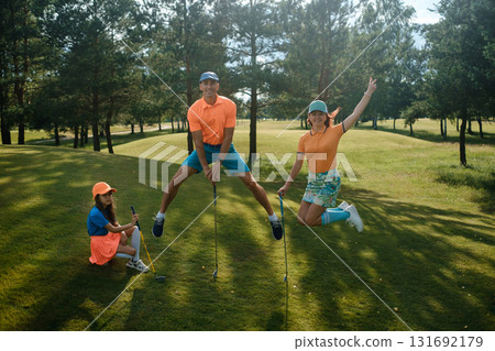 Group of friends enjoying a playful moment on a golf course during a sunny afternoon featuring colorful golf attire and a lush green landscape Group of friends enjoying a playful moment on a golf course during a sunny afternoon featuring colorful golf attire and a lush green landscape 131692179