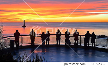 Silhouetted Figures Admire Fiery Sunset Over Ocean with Distant 131692332