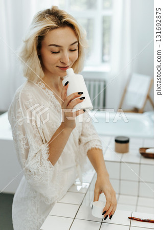 Young caucasian woman smells the aroma of a new shampoo and shower gel in a plastic bottle 131692875