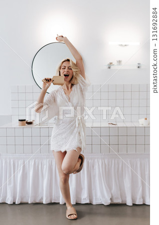 Young woman singing with comb as mic and dancing at home bathroom 131692884