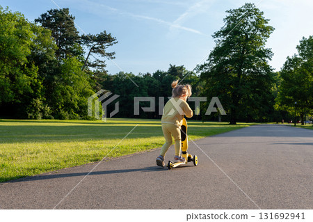 Girl on scooter. Riding child outdoor fun. Sunshine road freedom lifestyle. 131692941