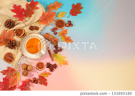 Bright autumn flyer with a cup of tea or mulled wine, maple leaves, pine cones, nuts, cinnamon, star anise and dried oranges, abstract seasonal composition and still life, Thanksgiving concept, 131693180