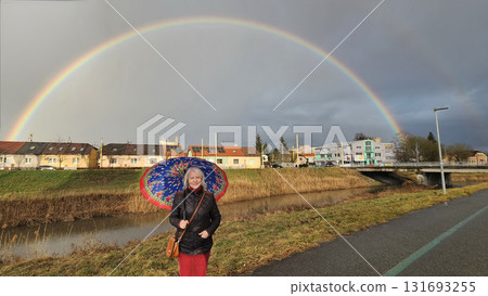 woman with  colorful umbrella and rainbow in the background 131693255