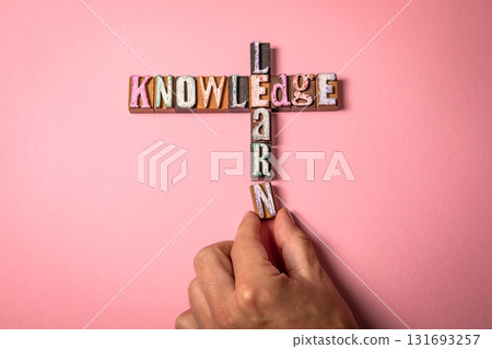 Knowledge and Learn concept on a pink background, with a hand placing the final letter Knowledge and Learn concept on a pink background, with a hand placing the final letter 131693257