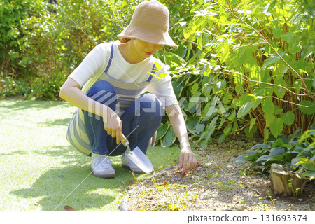 A woman in an apron tending to her garden 131693374