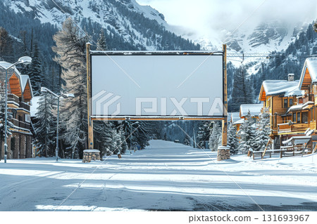 Blank billboard stands on snow-covered street between wooden cabins with snowy mountains in background. Concept of advertising, winter, nature. For winter holiday promotion 131693967