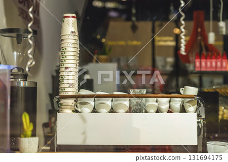 Stack of paper and ceramic coffee cups placed on an espresso machine inside cozy cafe. Concept of coffee, lifestyle reflecting warmth, routine, modern urban culture Stack of paper and ceramic coffee cups placed on an espresso machine inside cozy cafe. Concept of coffee, lifestyle reflecting warmth, routine, modern urban culture 131694175