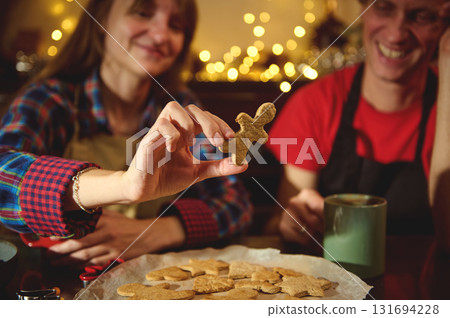 Family Friends Baking Christmas Cookies: Holding A Gingerbread Man In A Cozy Kitchen With Holiday Lights 131694228