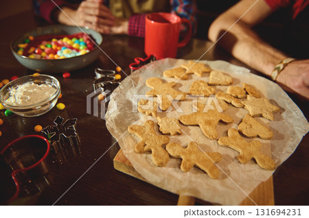 Family Cookies Night: Gingerbread Figures, Dough, Cutters, and Colorful Candies on a Wooden Table Family Cookies Night: Gingerbread Figures, Dough, Cutters, and Colorful Candies on a Wooden Table 131694231